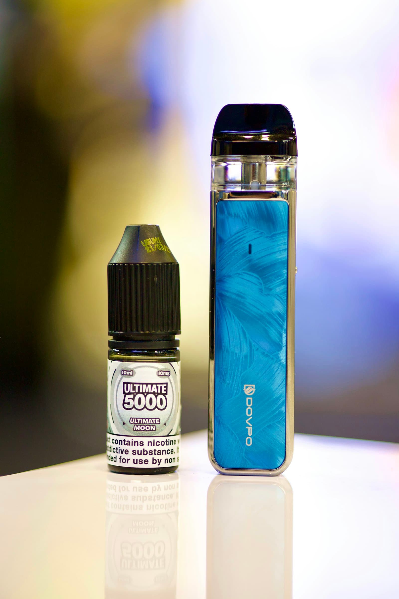 A 10ml nicotine salt e-liquid bottle showing its strength label standing next to a compact pod-system vape device