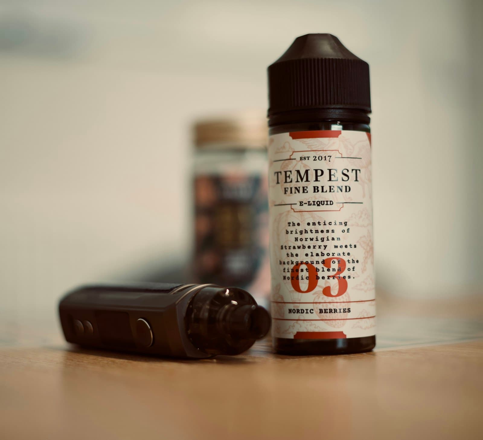 A pod vape device next to a small e-liquid bottle being used to refill it
